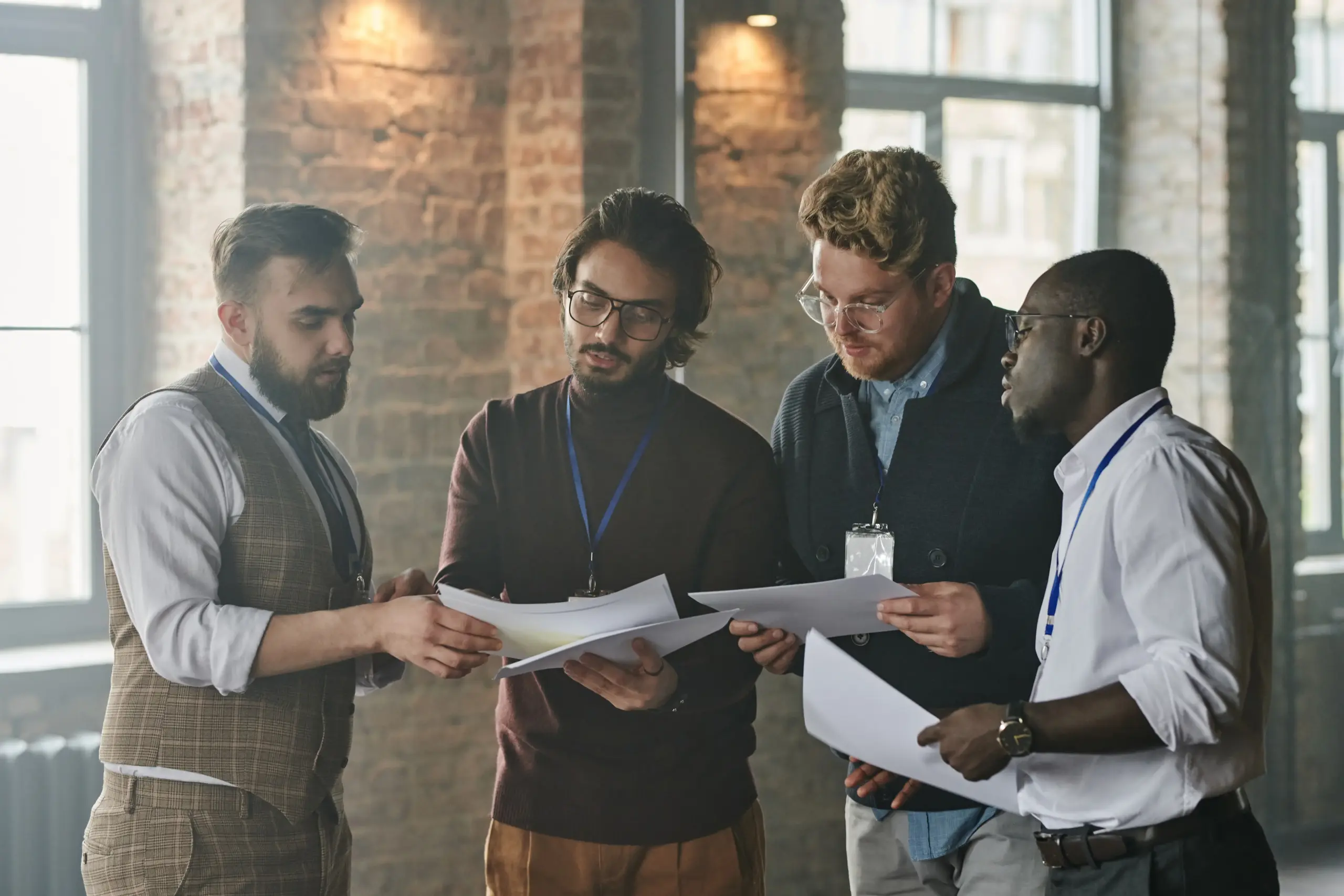 Four business partners looking over papers together as they stand in a semi circle.