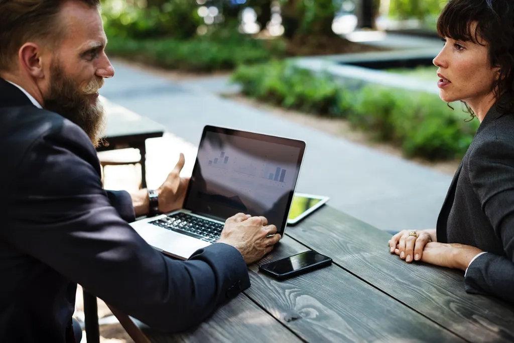 A man working on his laptop looking angrily at a woman across from him.