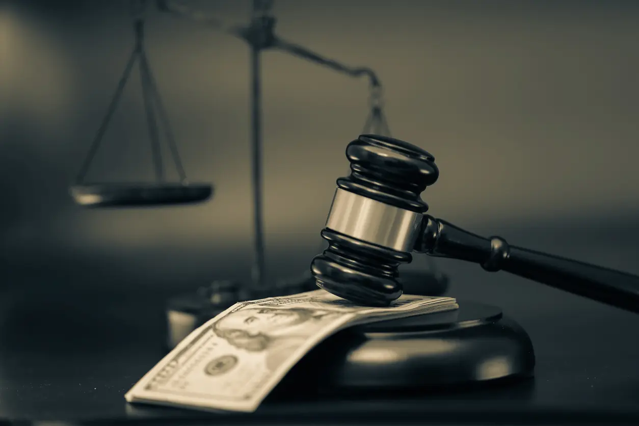 A small stack of money sits under a gavel on the desk of a Houston fraud lawyer.