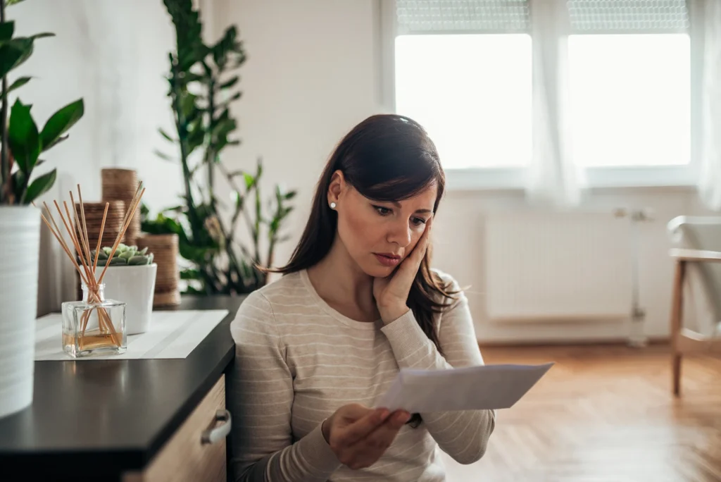 A woman looking at paperwork in shock.