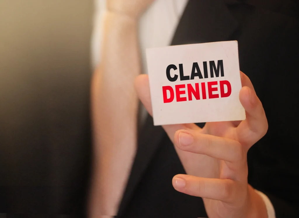 Man holding up a paper that says claim denied.