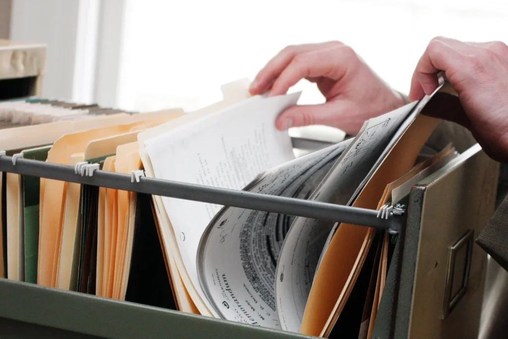 Hands looking through filing cabinet.